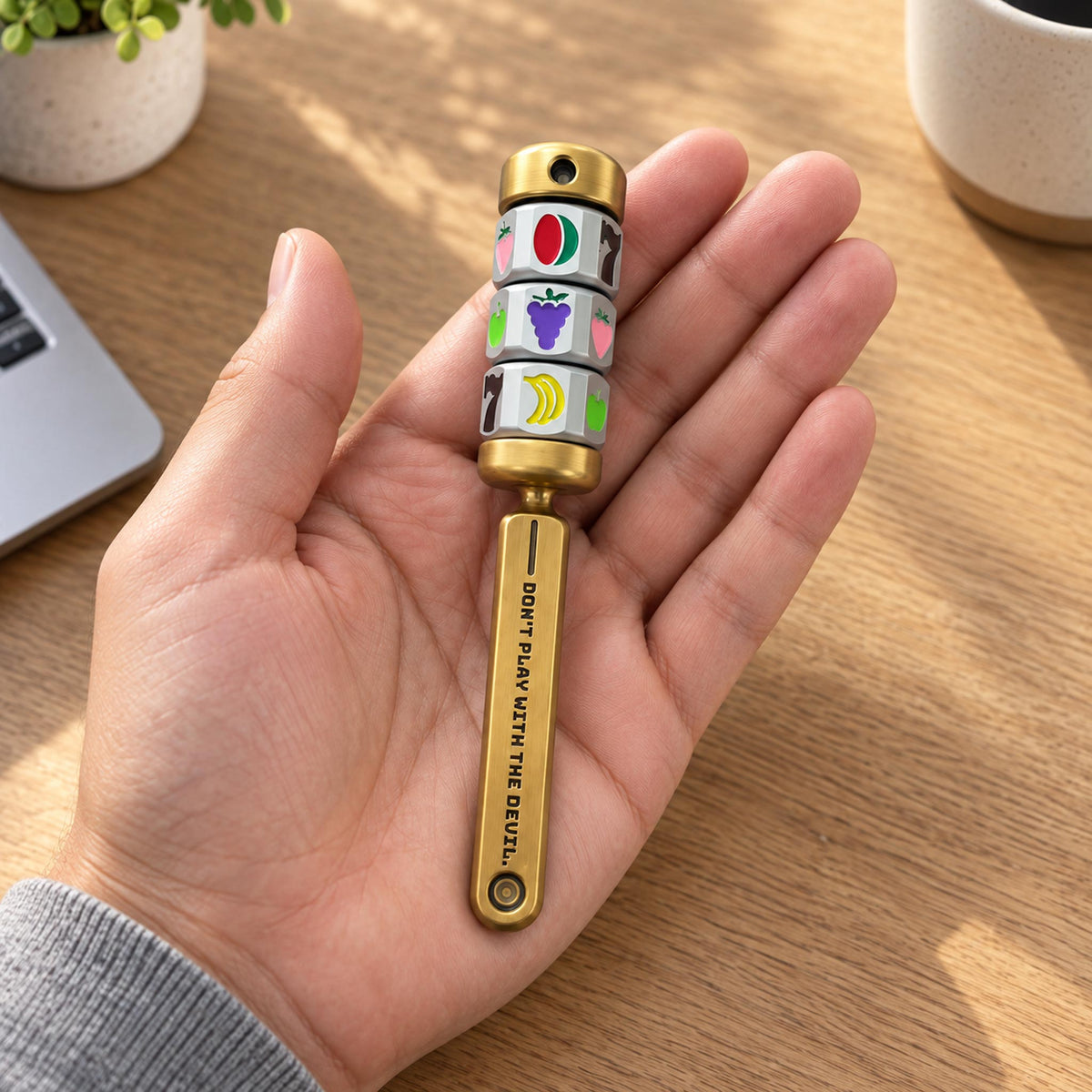 Adult hand holding and spinning triple jackpot reels on brass fidget baton