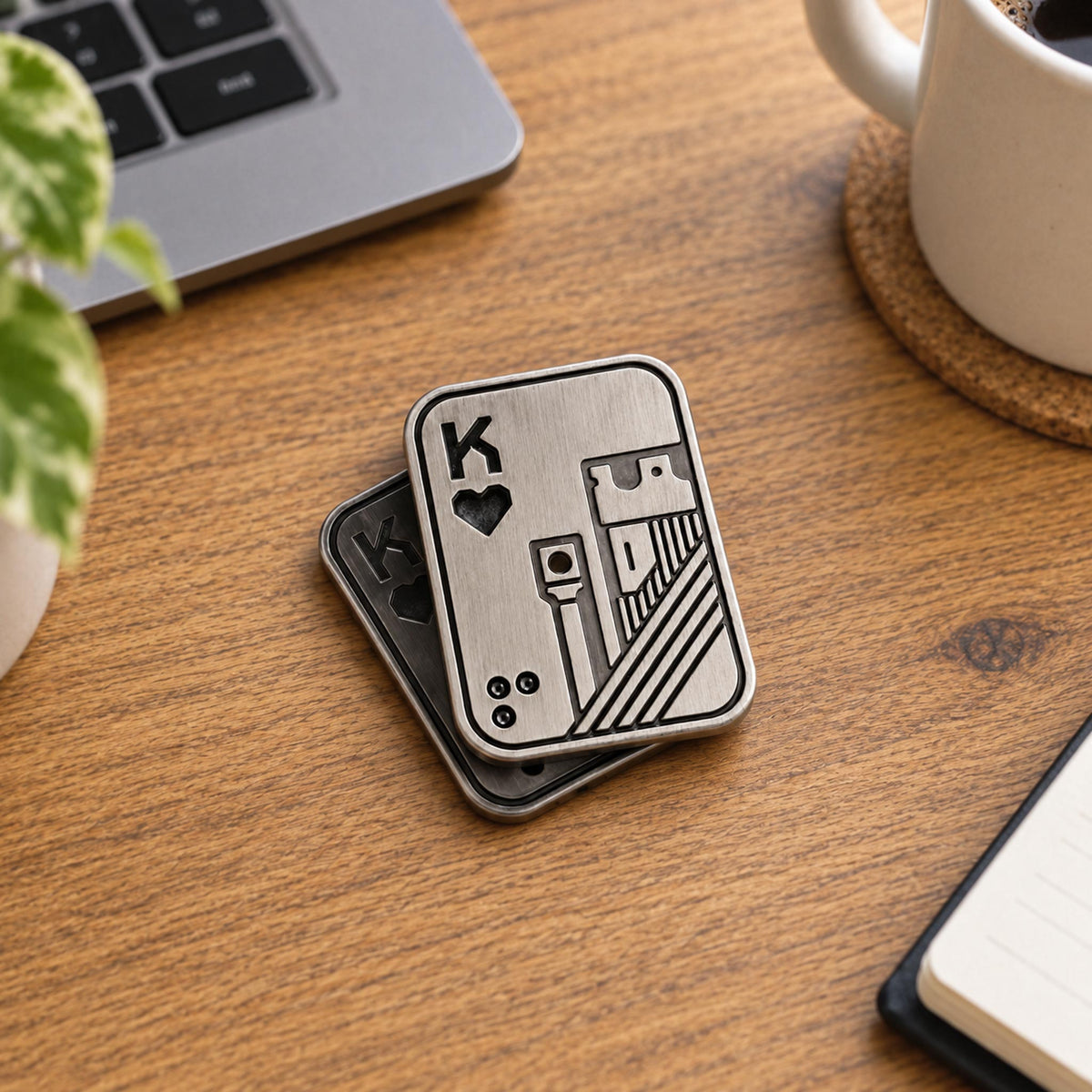 Pair of silver and bronze King of Spades metal fidget sliders on desk mat