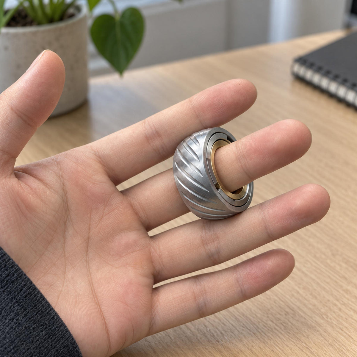 Hand spinning metal mechanical EDC ring during focused office desk work session