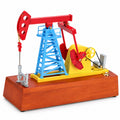Red and blue kinetic oil pumpjack model on wooden base on white background