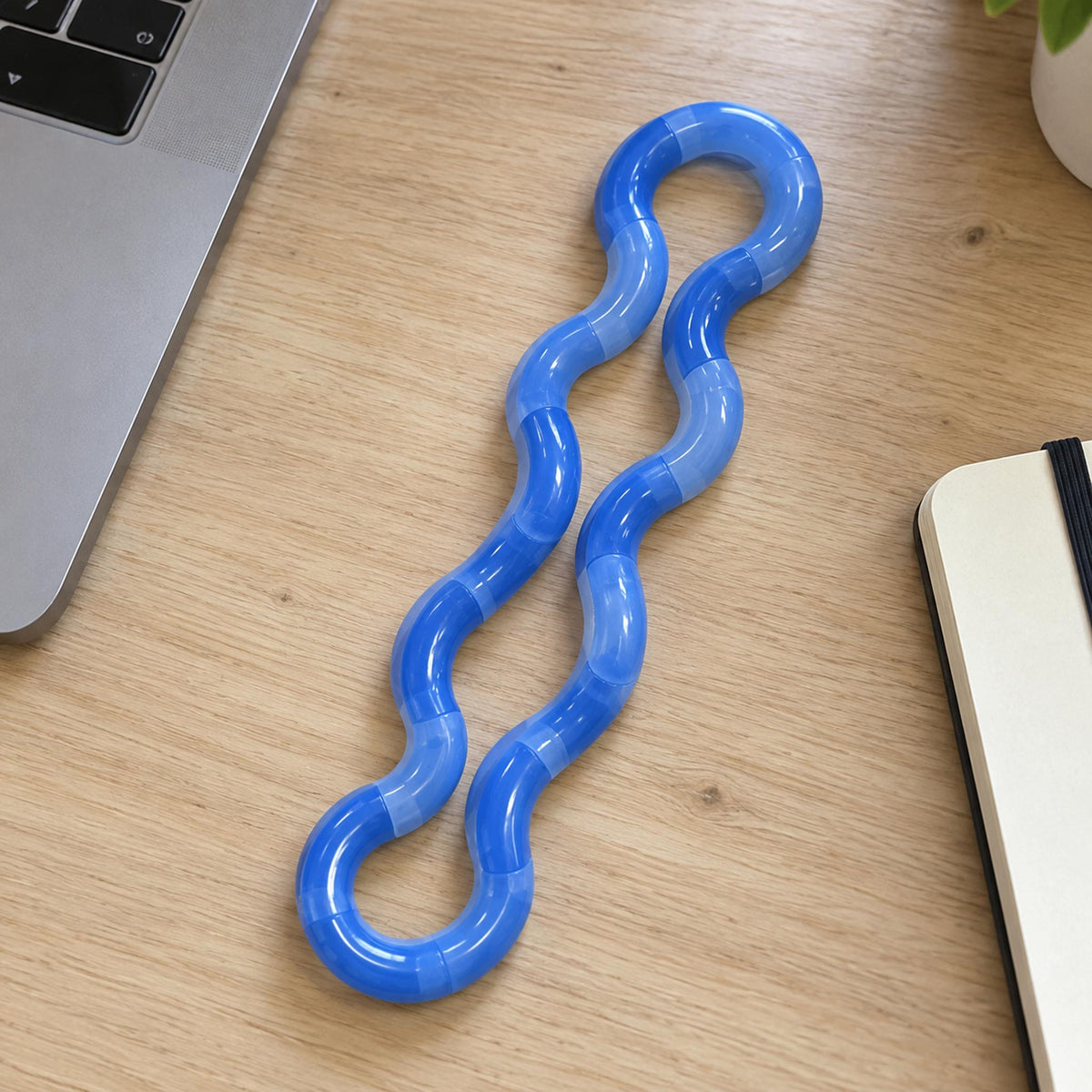 Hand holding extended blue thermochromic twist fidget toy at modern office desk